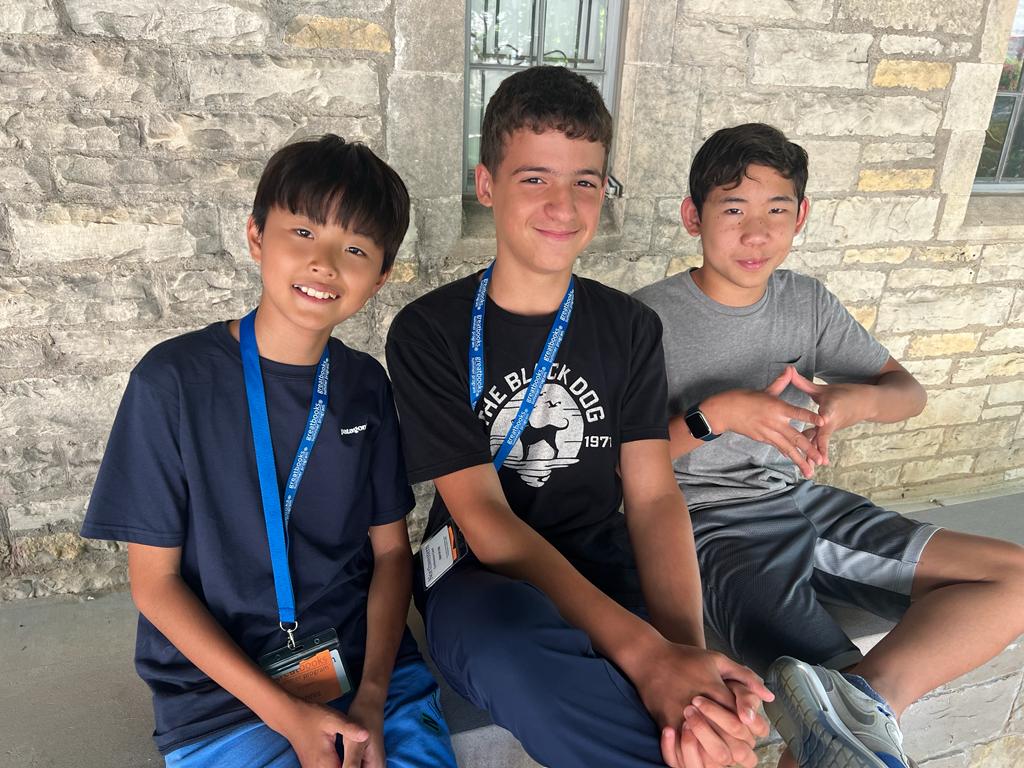 Northwestern three young boys sitting in front of stone wall